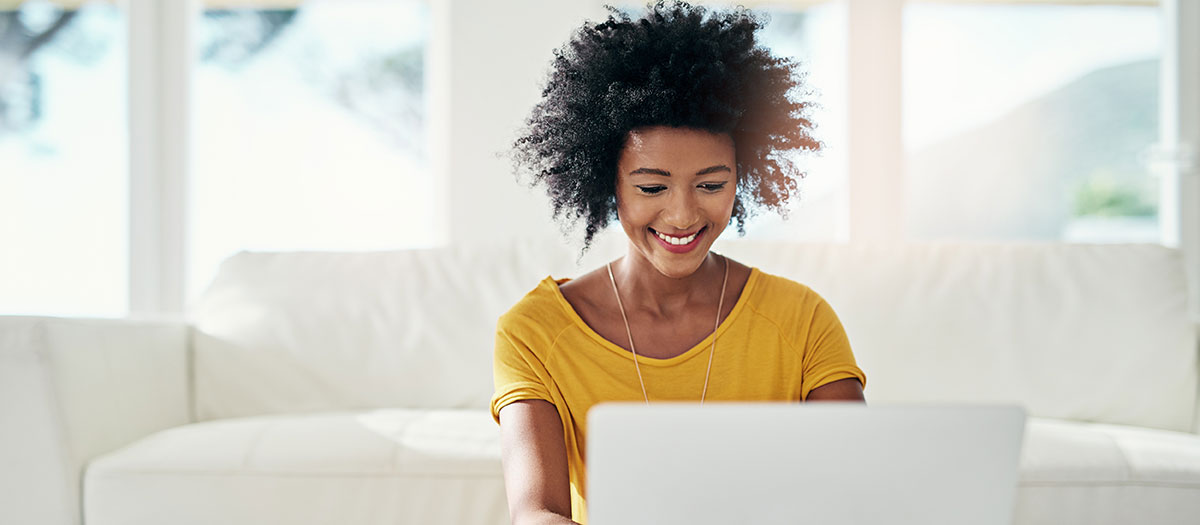 Woman smiling, looking at laptop