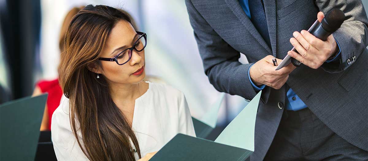 A young Asian business woman showing a document to business man in meeting.