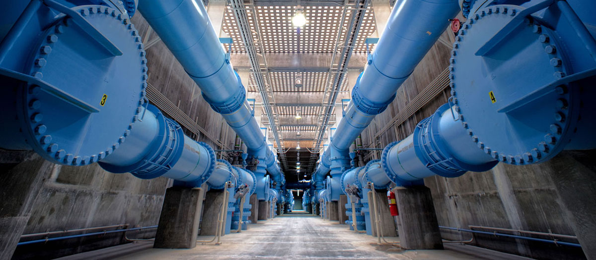 Blue transmission pipes run down the length of a hallway at the River Mountains Water Treatment Facility