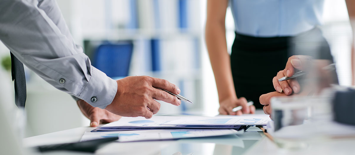 People standing around table reviewing paperwork