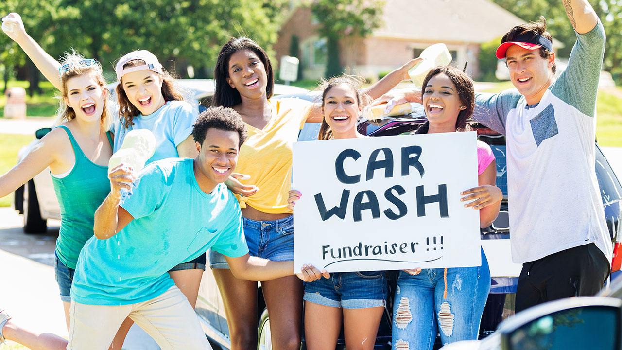 Teenagers holding sign for car wash fundraiser