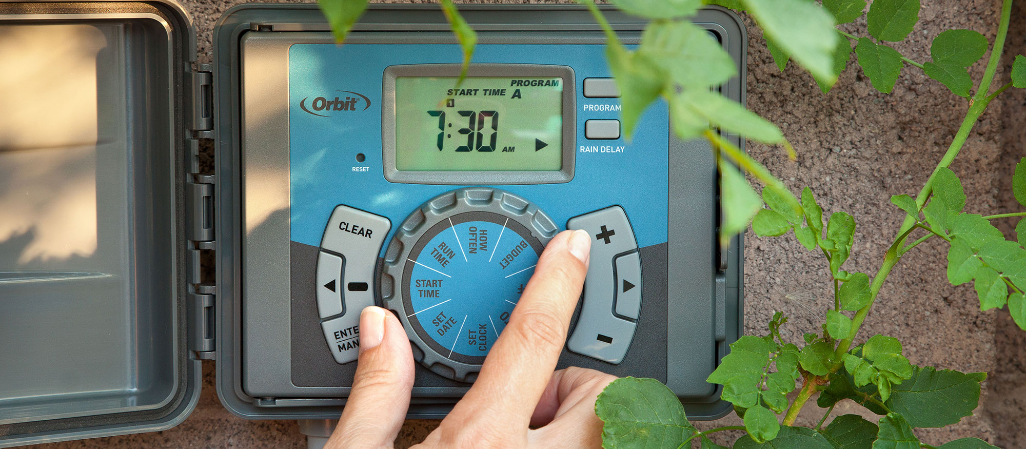 Hand turns dial on irrigation clock