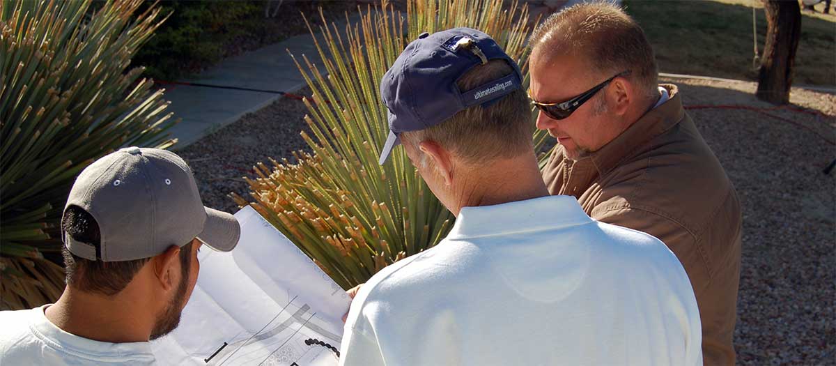 men looking over plans for landscape conversion