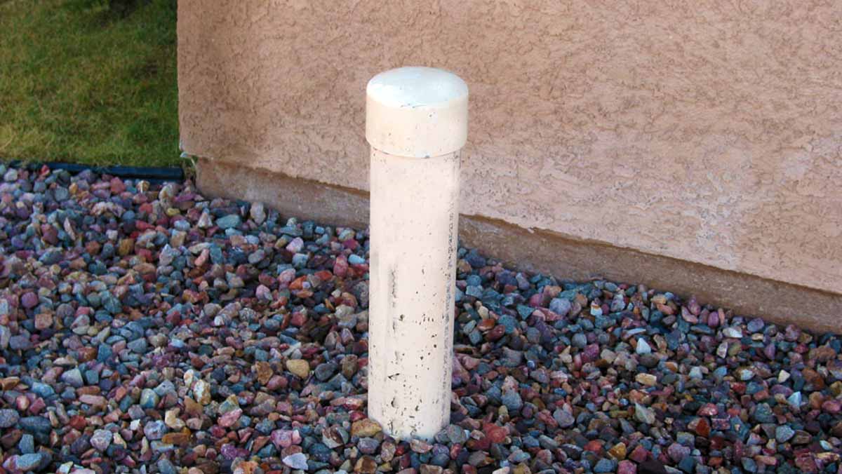 A pool cleanout port in gravel in a front yard