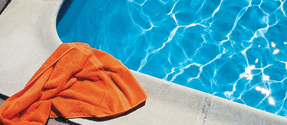 Swimming pool with orange towel laying on edge