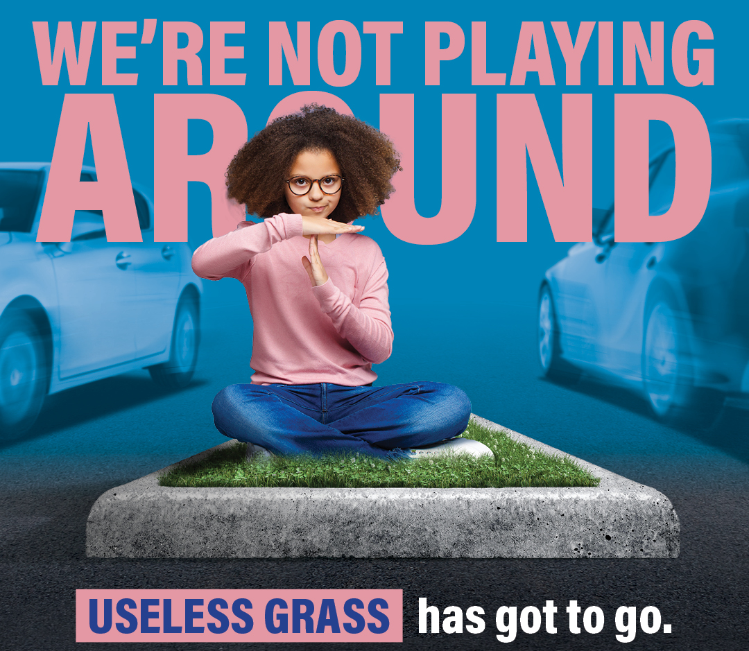 Girl making "time out" gesture with her hands while sitting on patch of grass in median. Text says "we're not playin around. useless grass has got to go"