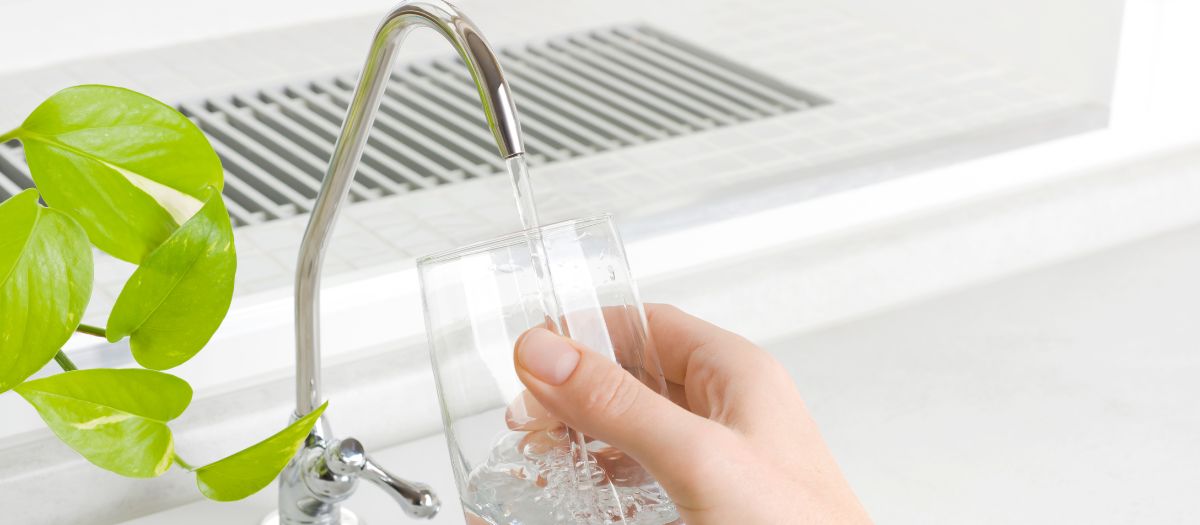 water filters in kitchen next to glass of water in front of window