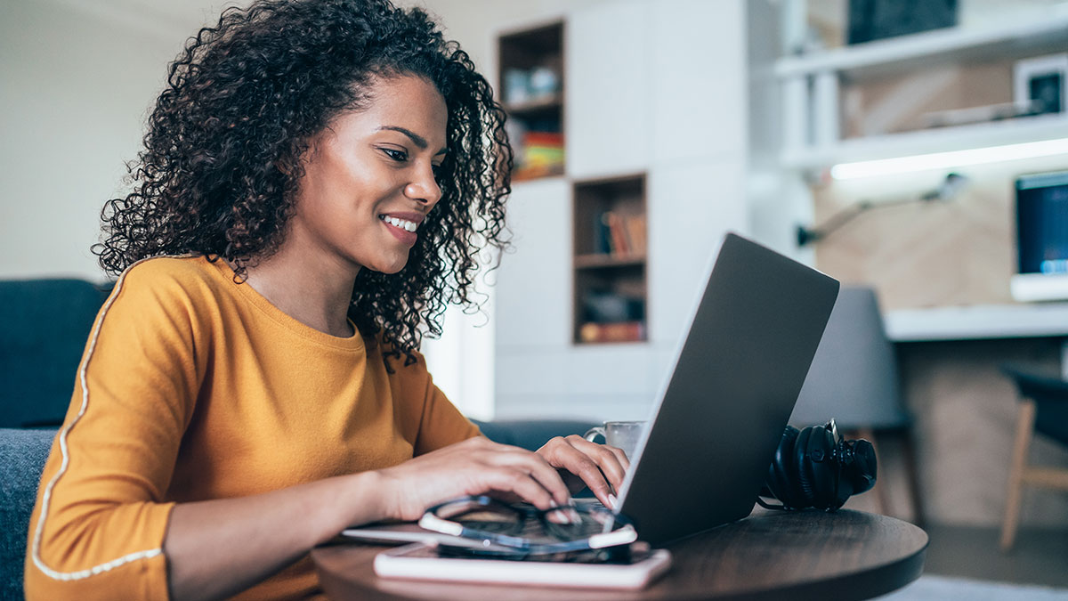 A black woman in a yellow top using a computer